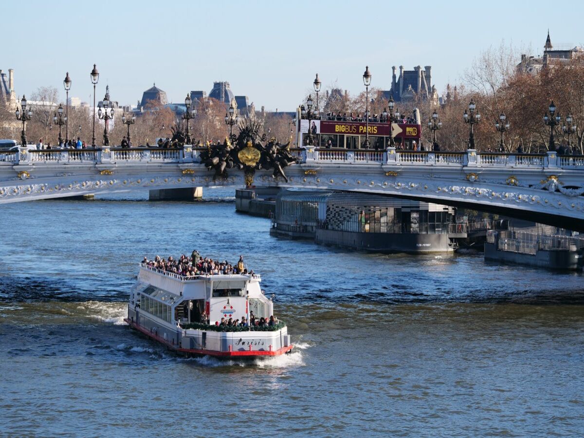 A boat traveling down a river next to a bridge